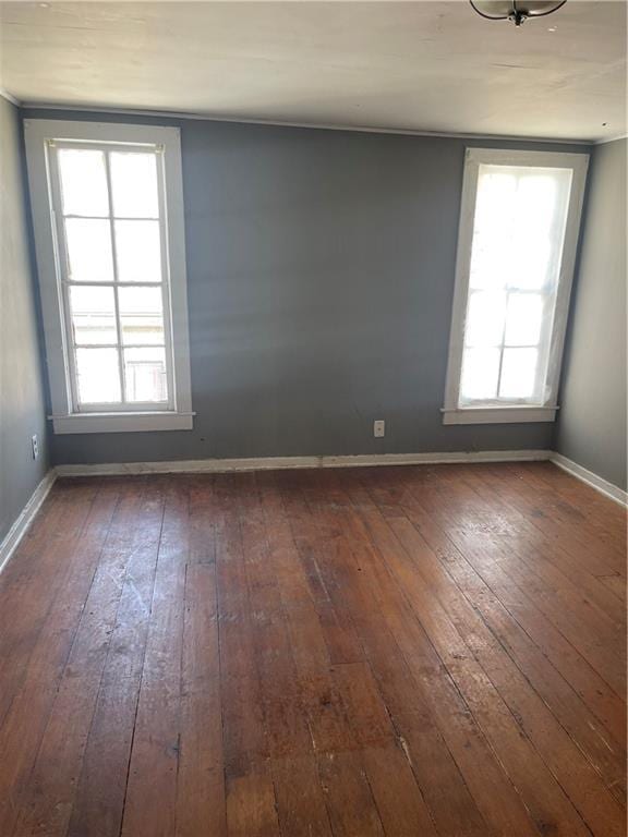 unfurnished room featuring baseboards, wood-type flooring, and a healthy amount of sunlight