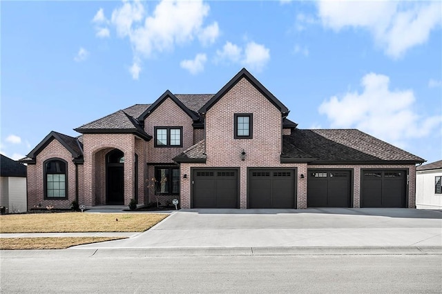 2171 NW Palisades Dr, Riverside, MO 64150 - french country home featuring concrete driveway, brick siding, and an attached garage