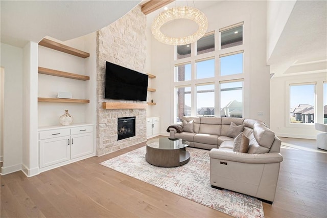 2171 NW Palisades Dr, Riverside, MO 64150 - living room featuring hardwood / wood-style floors, a stone fireplace, built in features, a high ceiling, and baseboards