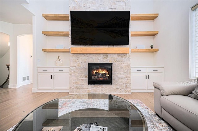 2171 NW Palisades Dr, Riverside, MO 64150 - living room featuring light wood finished floors, a fireplace, arched walkways, and baseboards