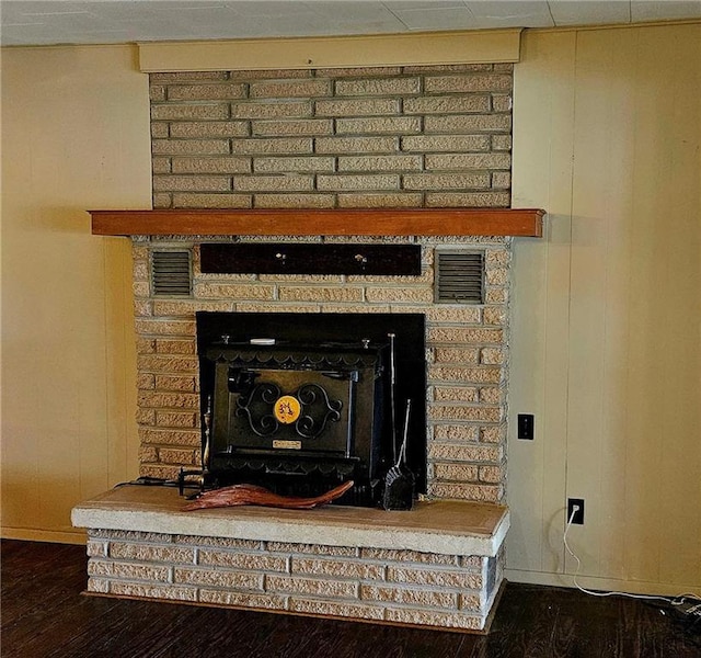 detailed view of a fireplace, wood finished floors, and baseboards