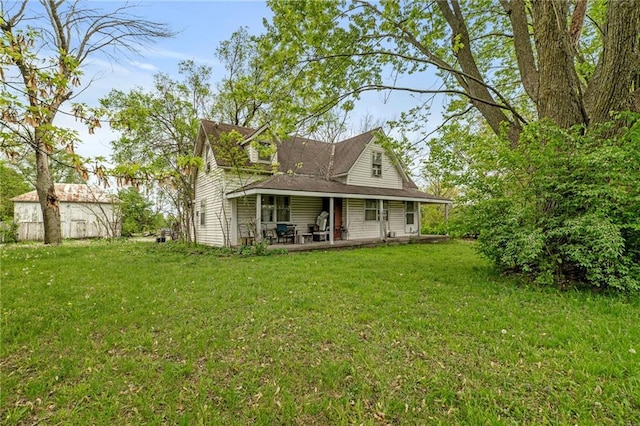 rear view of house with an outdoor structure, covered porch, and a yard
