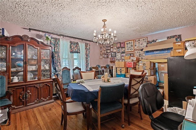 dining room featuring a chandelier, wood finished floors, and a textured ceiling