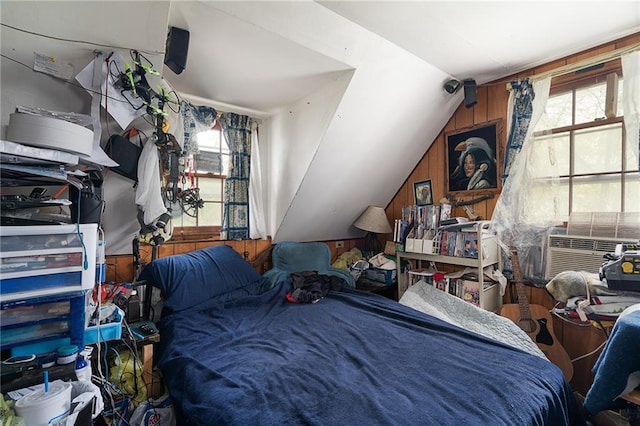 bedroom featuring wooden walls, multiple windows, and vaulted ceiling