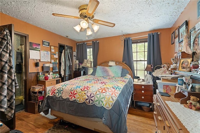 bedroom with a textured ceiling, wood finished floors, and ceiling fan