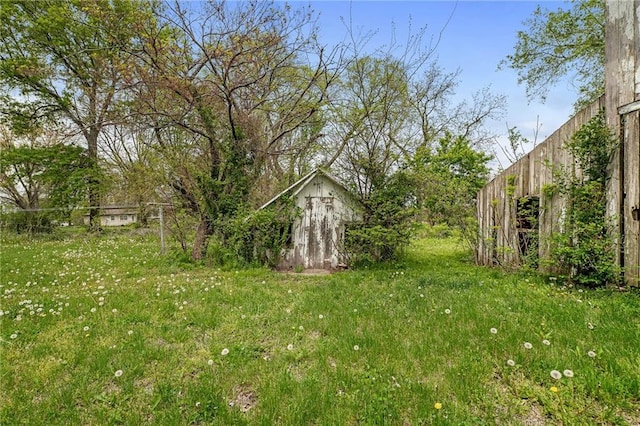 view of yard with an outdoor structure, a storage shed, and fence