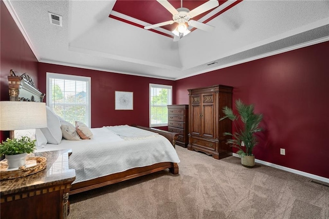 bedroom with a raised ceiling, carpet flooring, crown molding, baseboards, and a ceiling fan