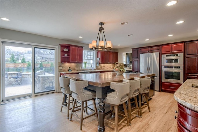 10318 Sagamore Rd, Leawood, KS 66206 - kitchen featuring stainless steel appliances, dark brown cabinets, light wood finished floors, a kitchen island, and recessed lighting