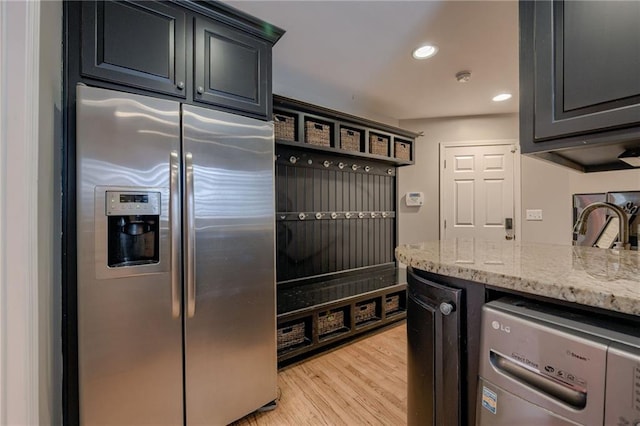 10318 Sagamore Rd, Leawood, KS 66206 - kitchen featuring stainless steel fridge with ice dispenser, washer / dryer, light stone counters, light wood finished floors, and recessed lighting