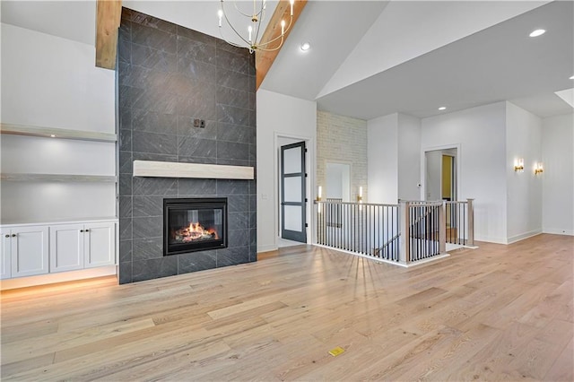 24936 W 98th Pl, Lenexa, KS 66227 - unfurnished living room featuring high vaulted ceiling, wood finished floors, a tiled fireplace, a chandelier, and recessed lighting
