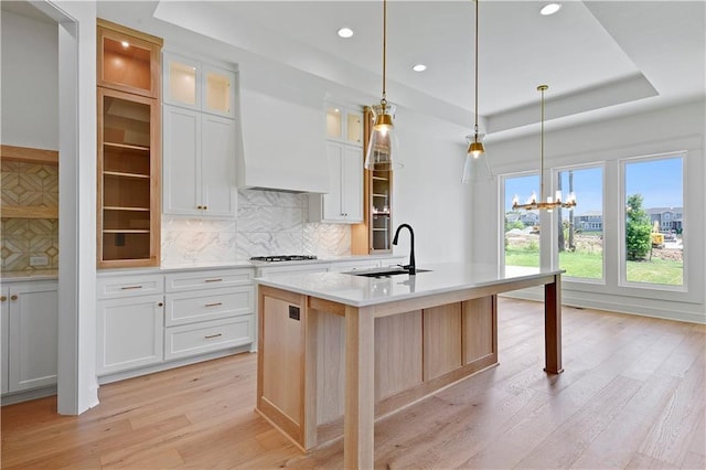 24936 W 98th Pl, Lenexa, KS 66227 - kitchen featuring a tray ceiling, light wood-style floors, light countertops, gas stovetop, and tasteful backsplash