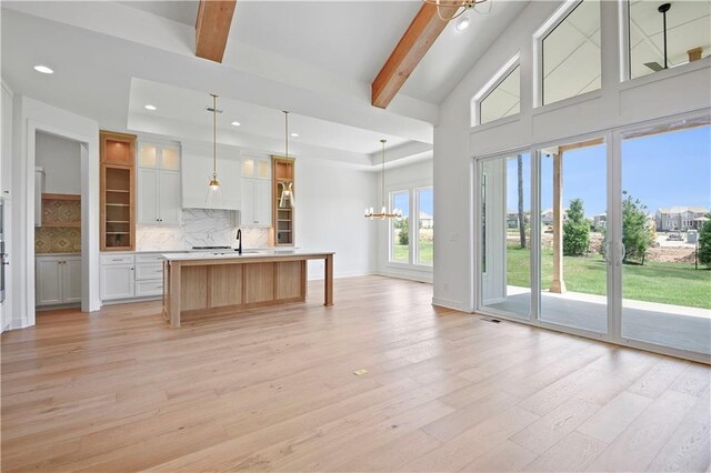 24936 W 98th Pl, Lenexa, KS 66227 - kitchen with a chandelier, light countertops, light wood-style flooring, backsplash, and an island with sink