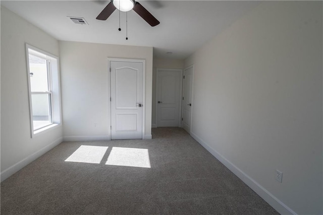 1702 N 2nd St, Neodesha, KS 66757 - unfurnished bedroom with visible vents, light carpet, baseboards, and a ceiling fan