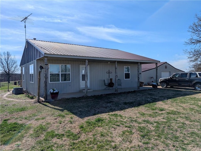 back of property with cooling unit, a yard, covered porch, a garage, and metal roof