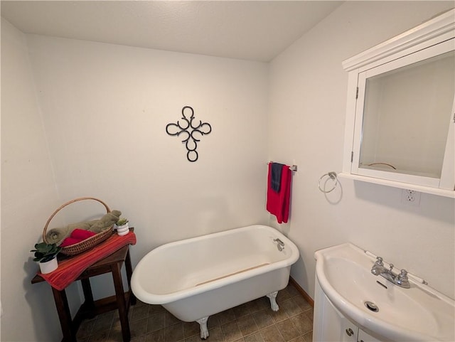 full bath with a freestanding bath, vanity, and baseboards