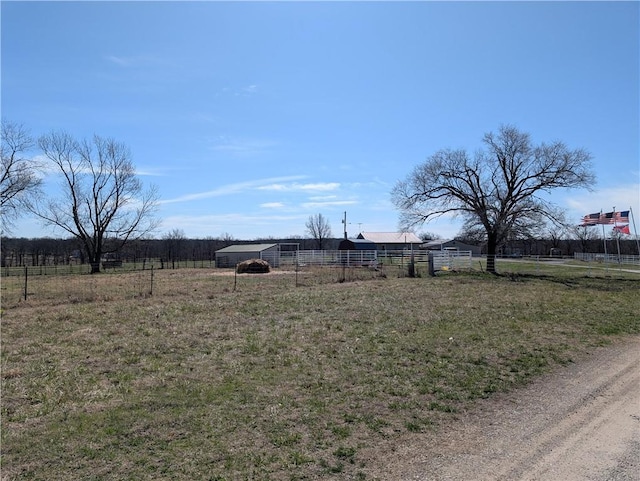 view of yard with a rural view, an outdoor structure, and fence