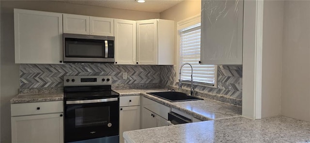 kitchen featuring a sink, tasteful backsplash, white cabinetry, and stainless steel appliances