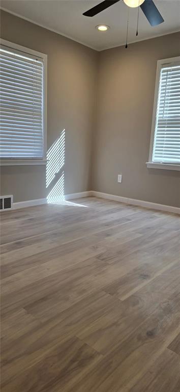 unfurnished room with visible vents, baseboards, a ceiling fan, and wood finished floors