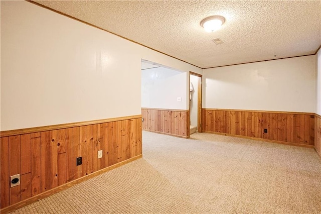 3402 Messanie St, Saint Joseph, MO 64501 - unfurnished room with wainscoting, a textured ceiling, wooden walls, ornamental molding, and light colored carpet