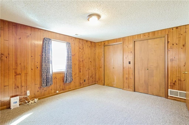 3402 Messanie St, Saint Joseph, MO 64501 - unfurnished bedroom with carpet floors, multiple closets, wooden walls, and a textured ceiling
