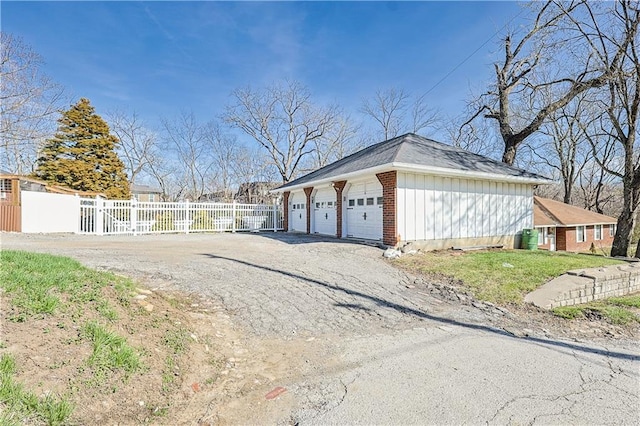 3402 Messanie St, Saint Joseph, MO 64501 - view of property exterior with fence, a detached garage, board and batten siding, an outdoor structure, and brick siding