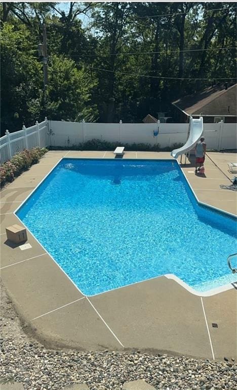 3402 Messanie St, Saint Joseph, MO 64501 - view of swimming pool with a water slide, a fenced backyard, a patio, a diving board, and view of scattered trees