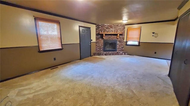 616 E Jackson E, Jackson, Pittsburg, KS 66762 - unfurnished living room with carpet flooring, a brick fireplace, crown molding, and visible vents