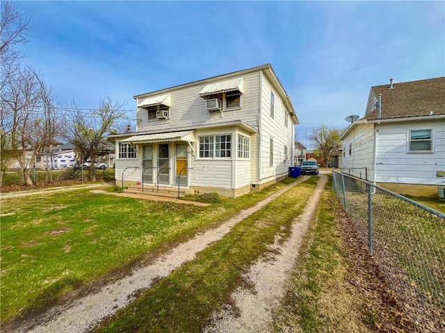 rear view of house with a lawn, fence, and dirt driveway