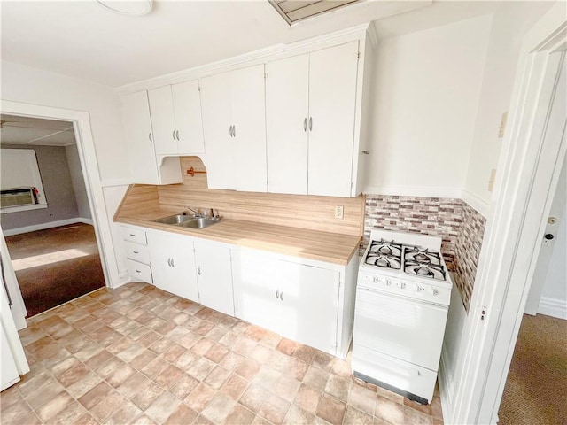 kitchen with a sink, gas range gas stove, backsplash, white cabinetry, and light countertops