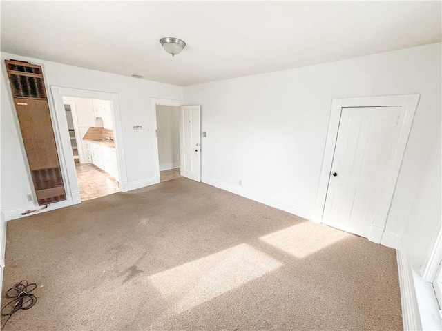 unfurnished bedroom featuring connected bathroom, baseboards, and light colored carpet
