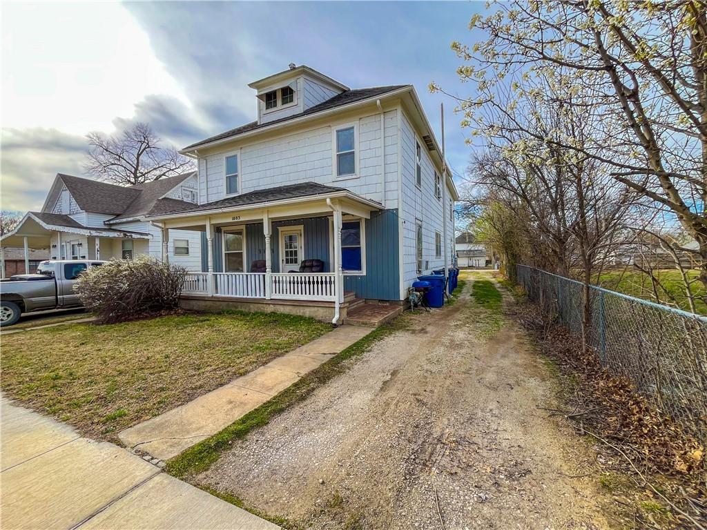 1003 W 9th St, Coffeyville, KS 67337 - traditional style home with a front lawn, a porch, driveway, and fence