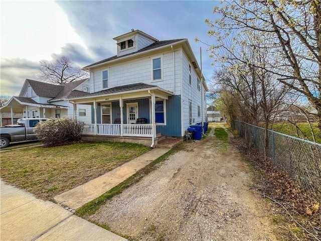 traditional style home with a front lawn, a porch, driveway, and fence