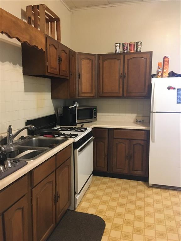 159 S Jewell St, Liberty, MO 64068 - kitchen with decorative backsplash, white appliances, light floors, light countertops, and a sink