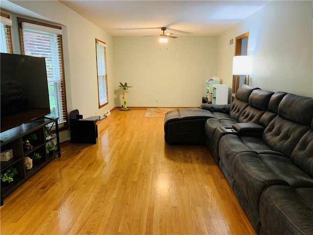 living room featuring baseboards, a ceiling fan, light wood-style flooring, and visible vents