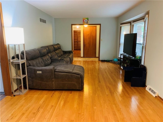 living area with visible vents and wood finished floors