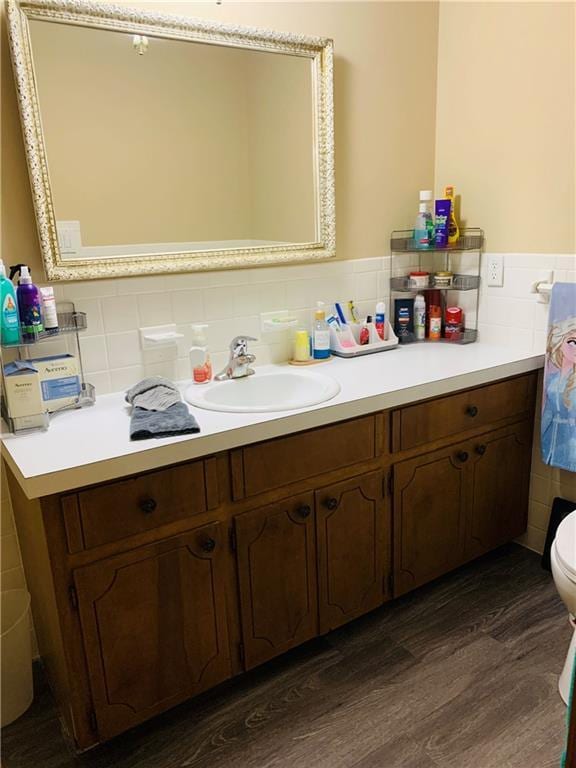 bathroom featuring vanity, toilet, a wainscoted wall, tile walls, and wood finished floors