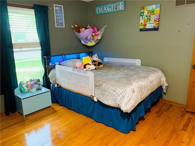 bedroom featuring baseboards, visible vents, and wood finished floors