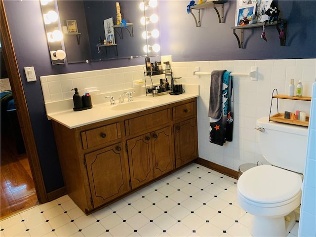 bathroom with tile patterned floors, vanity, toilet, and tile walls