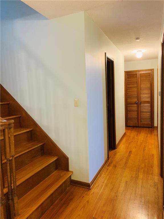 hall featuring baseboards, stairs, and light wood-style flooring