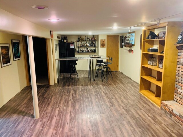 interior space featuring a bar, freestanding refrigerator, wood finished floors, and track lighting