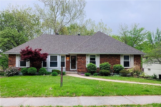 ranch-style home with brick siding, roof with shingles, and a front yard