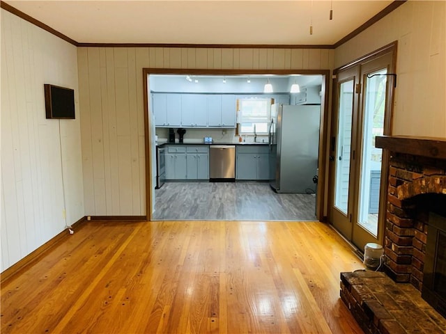 kitchen featuring crown molding, dark countertops, a sink, light wood-style floors, and stainless steel appliances