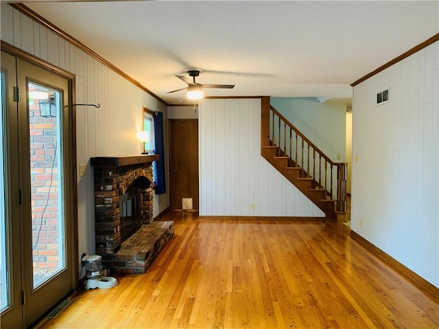 unfurnished living room with crown molding, wood walls, and wood finished floors