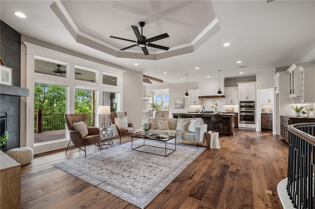 9238 Marion St, Lenexa, KS 66220 - living room with ceiling fan, recessed lighting, dark wood finished floors, a tiled fireplace, and a raised ceiling