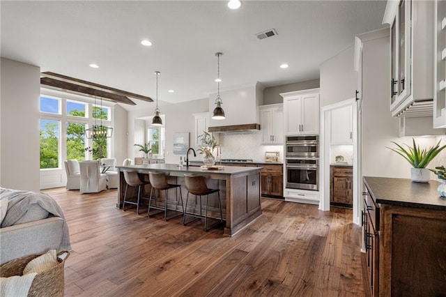 9238 Marion St, Lenexa, KS 66220 - kitchen with double oven, a breakfast bar, backsplash, dark wood-type flooring, and a center island with sink