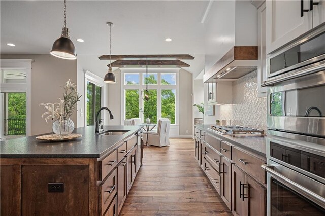 9238 Marion St, Lenexa, KS 66220 - kitchen with a sink, dark countertops, wood-type flooring, wall chimney range hood, and recessed lighting