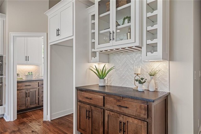 9238 Marion St, Lenexa, KS 66220 - kitchen featuring decorative backsplash, dark countertops, glass insert cabinets, and white cabinets