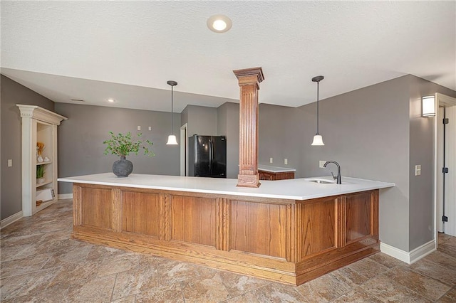 15511 Salem Rd, Excelsior Springs, MO 64024 - kitchen with freestanding refrigerator, decorative columns, a sink, brown cabinetry, and baseboards