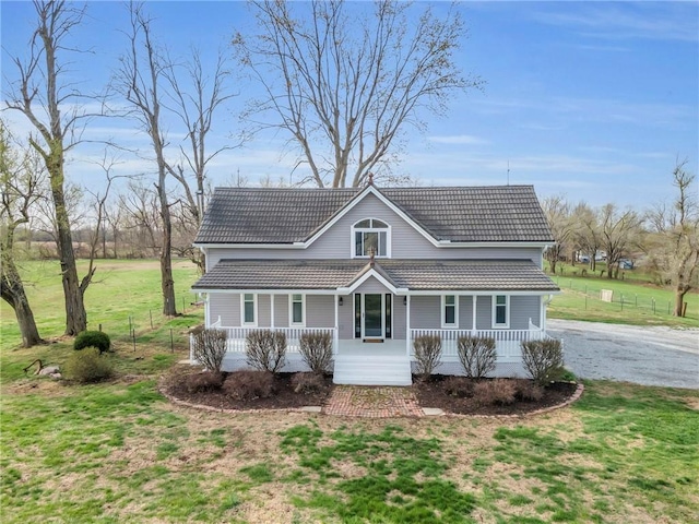 traditional home featuring a front yard, a tile roof, a porch, and driveway