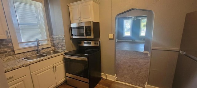 224 Spruce St, Leavenworth, KS 66048 - kitchen featuring a sink, appliances with stainless steel finishes, white cabinets, dark colored carpet, and decorative backsplash